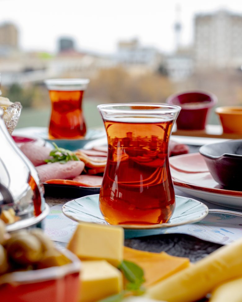 Türkischer Tee auf einem reich gedeckten Frühstückstisch mit Stadtblick im Hintergrund